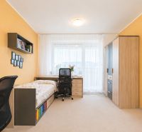 A room with light walls, wooden decor furniture, and a bed in a 3-room apartment.