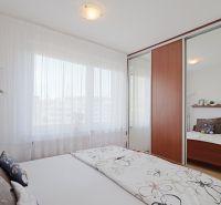 Bedroom in a 3-room apartment with a large mirrored wardrobe and delicate curtains.
