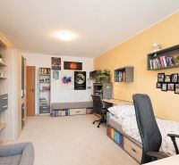 A children's room in a 3-room apartment with wooden decor, featuring a desk and a bed.