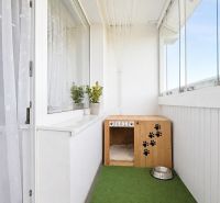 Glazed balcony with a box for a dog and a bowl in a 3-room apartment.