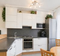 A kitchen in a 3-room apartment with white cabinets, a corner sink, and a dining table.