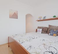Bedroom in a 3-room apartment with a bed, pillows, and a shelf on white walls.