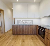 A kitchen in a 2-room apartment with a wooden decor floor and white cabinets.
