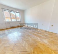 A spacious room with windows and a wooden decor floor in a 2-room apartment.