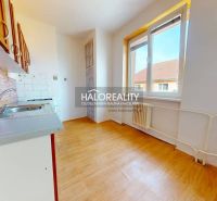 A kitchen in a 2-room apartment with a wooden decor floor and a view from the window.