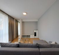 Living room in a three-room apartment with a sofa, glass table, and wooden decor flooring.