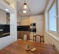 The interior of a kitchen in a 3-room apartment with light furniture and a wooden decor floor.