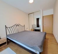 A bedroom with a metal bed, wood-decor flooring, and a built-in wardrobe in a three-room apartment.