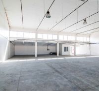 Interior of a warehouse space with a concrete floor and large windows.