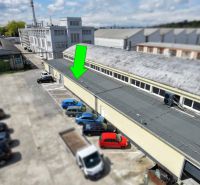 Warehouses and halls on Coburgova Street in Trnava with a parking lot and cars.