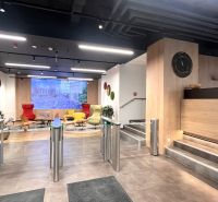 Interior of offices with modern seating, turnstiles, and flooring with wood decor.