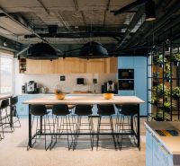 Offices with a large table, high chairs, plants, and a kitchenette.