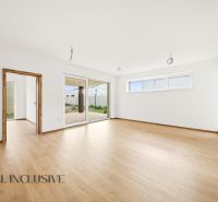 Spacious interior of a family house with a wooden decor floor and large windows.