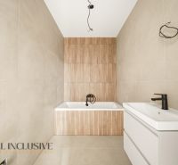 A bathroom with a bathtub and a sink in a family house with wooden decor paneling.