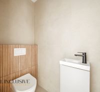 A bathroom in a family house with a wall featuring a wooden decor and a minimalist sink.