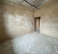 An unplastered room in a family house with a wooden decor floor.