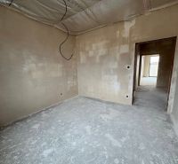 An unfinished interior of a family house with plastered walls and a raw floor.