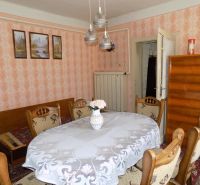 A dining room in a family house with retro furniture and floral wallpaper on the wall.
