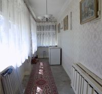 Interior of a family house with a hallway, carpet, and curtains on the windows.
