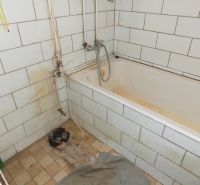 A bathroom in a family house with white tiles and an older bathtub.