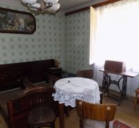 A room in a family house with furniture, a sewing machine, and a floor with a wood decor.