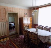 Dining room in a family house with carpet, curtains, and wooden furniture.