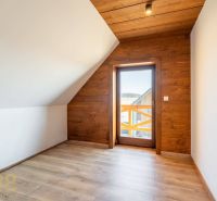 An attic room in a family house with a wooden decor floor and wooden paneling.