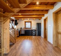 A kitchen in a family house with wooden ceilings, a floor with a wooden decor, and modern furniture.