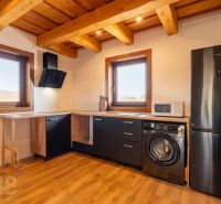 A kitchen in a family house with a wooden decor floor and black appliances.