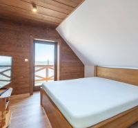 Bedroom of a family house with a bed and a television, floor with wooden decor.