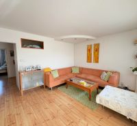 A living room in a 4-room apartment with a wooden decor floor and a comfortable sofa.
