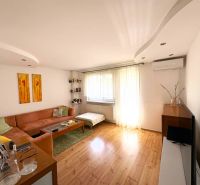 Living room with a sofa, wood-patterned flooring, and light-colored furniture in a 4-room apartment.