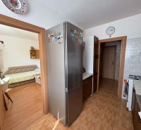 A kitchen with a refrigerator, stove, and wood-patterned flooring in a 4-room apartment.