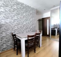 Dining room in a 3-room apartment with stone cladding and a wooden decor floor.