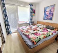 A bedroom in a 3-room apartment with a wooden decor floor and colorful bedding.