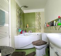 A bathroom in a 3-room apartment with a bathtub, sink, toilet, and green tiles.