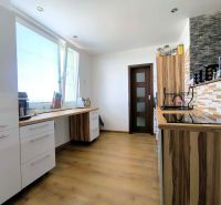 A kitchen in a 3-room apartment with a wooden decor floor, light cabinetry, and practical storage spaces.
