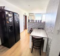 A kitchen with a dining table and a wall with stone decor in a 3-room apartment.