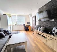 Living room with a sofa, television, and wooden decor flooring in a 3-room apartment.