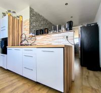 The kitchen of a 3-room apartment with white cabinets, wooden decor, and modern equipment.