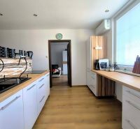 A kitchen in a 3-room apartment with a wooden decor floor and a large window.