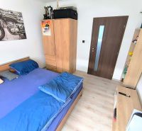 A bedroom in a three-room apartment with a wooden decor floor and furniture.