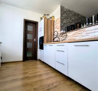 A kitchen in a 3-room apartment with white cabinets and a wood-patterned floor.