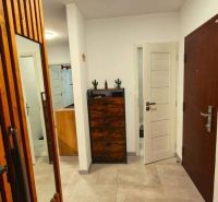 A hallway in a 3-room apartment with tiles, a mirror, and wooden furniture elements.