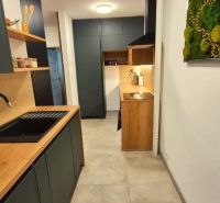 A kitchen in a 3-room apartment with a wood-patterned floor and white walls.