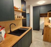 A kitchen in a 3-room apartment with a wood-patterned floor and modern storage space.