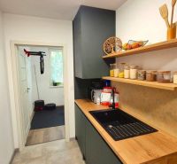 Kitchen shelves with food, wooden decor floor, view into the adjacent room.