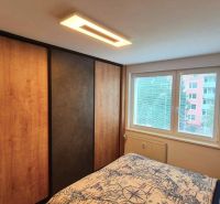Bedroom in a 3-room apartment with a large wardrobe, bed, and window. Floor with wood decor.