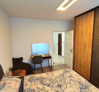 Bedroom with a bed featuring a map pattern, a desk, and a wardrobe in a 3-room apartment.