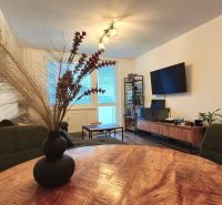 Living room in a three-room apartment with a TV, sofa, and table with decoration.